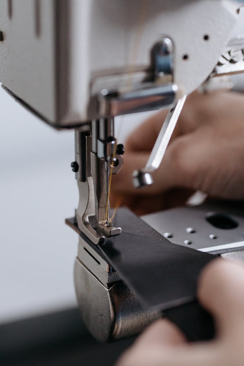 Detailed image of industrial sewing machine in use with leather fabric highlighting craftsmanship.